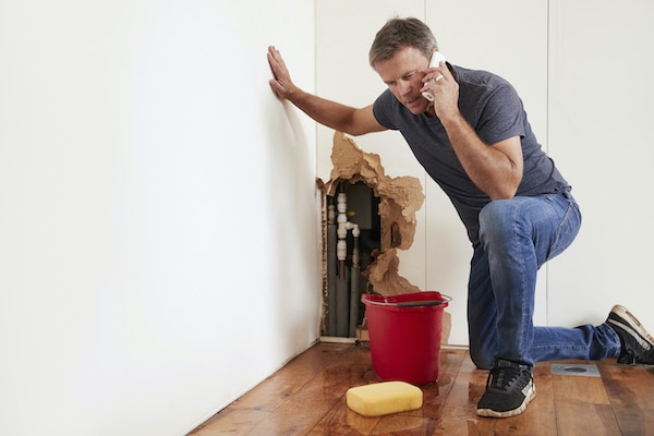 middle aged man calling an emergency plumber due to his broken pipes in the wall