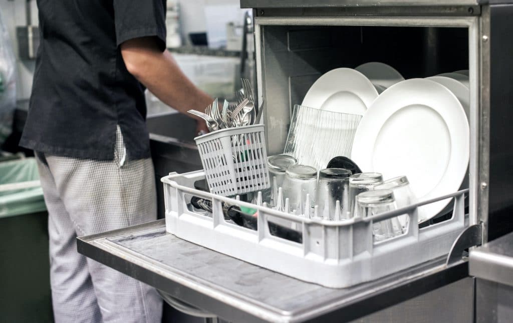 Kitchen hand with an open dishwasher