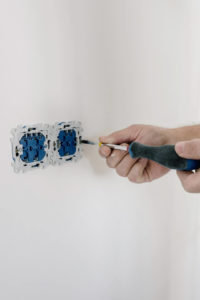 Electrician using screw to install an outlet at home