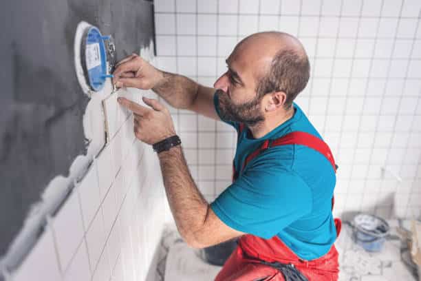 Professional tile worker putting spacers while installing tiles on the bathroom wall