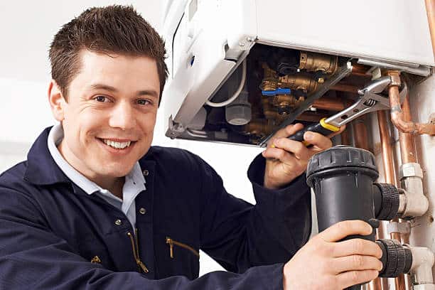 Male Plumber Working On water Heater Boiler.